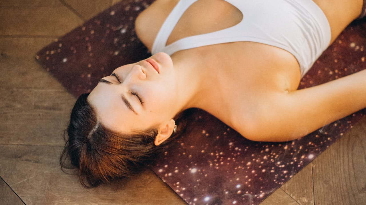 Femme relaxant sur un tapis de yoga avec bougies pour favoriser le sommeil