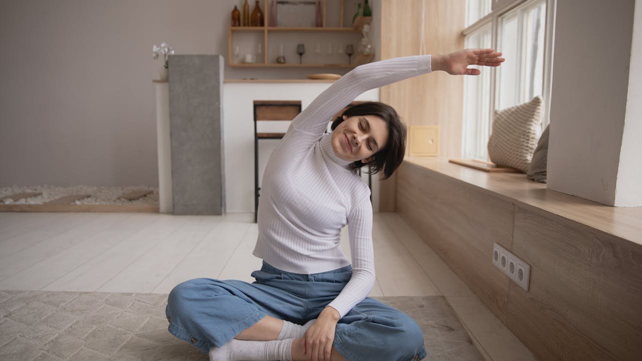 Femme souriante pratiquant le yoga chez elle avant de se coucher