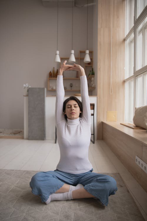 Femme assise pratiquant un étirement latéral yoga avec les bras levés