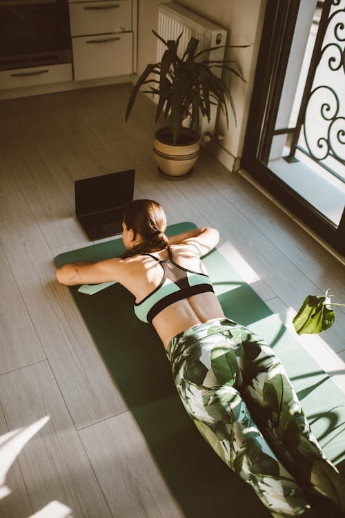 Femme en posture de Savasana relaxation finale sur un tapis de yoga vert