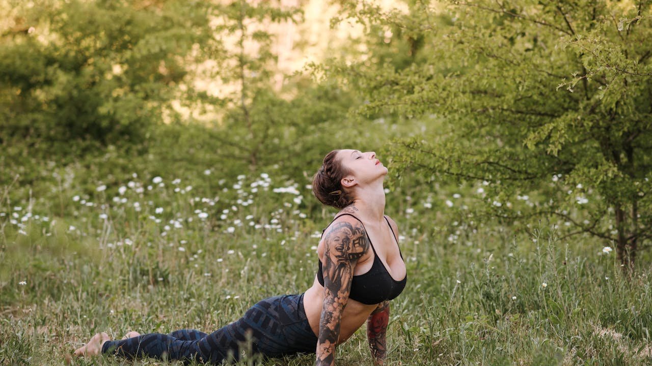 Femme pratiquant la posture du cobra yoga sur une pelouse verte en extérieur